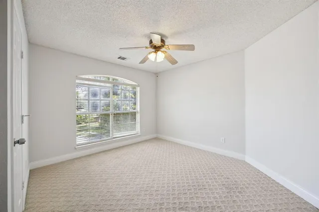 an empty room with chandelier fan and windows