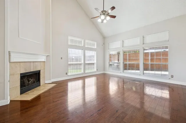 a view of an empty room with wooden floor and a fireplace