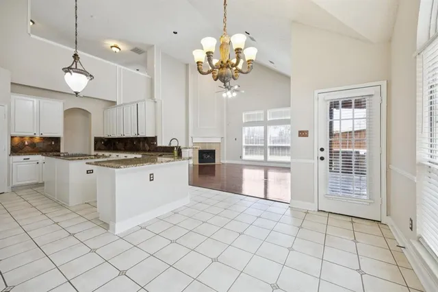 a kitchen with kitchen island granite countertop a stove a sink a refrigerator and chandelier