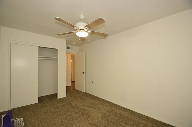 an empty room with a ceiling fan and a window