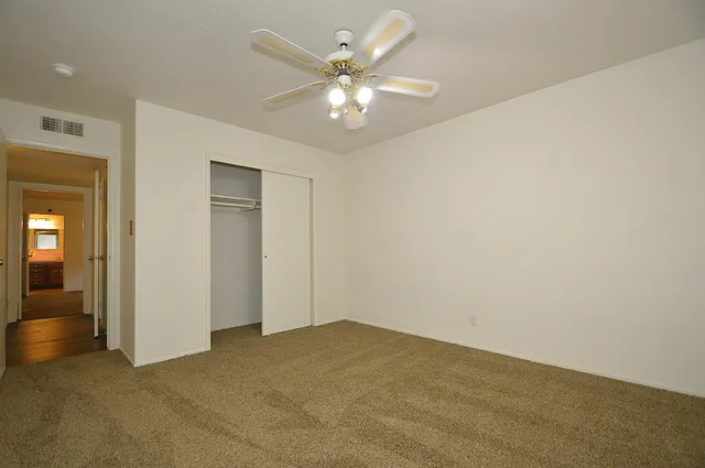 an empty room with a chandelier fan and windows