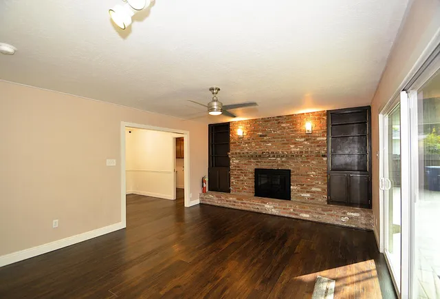 a view of a livingroom with wooden floor a fireplace and window