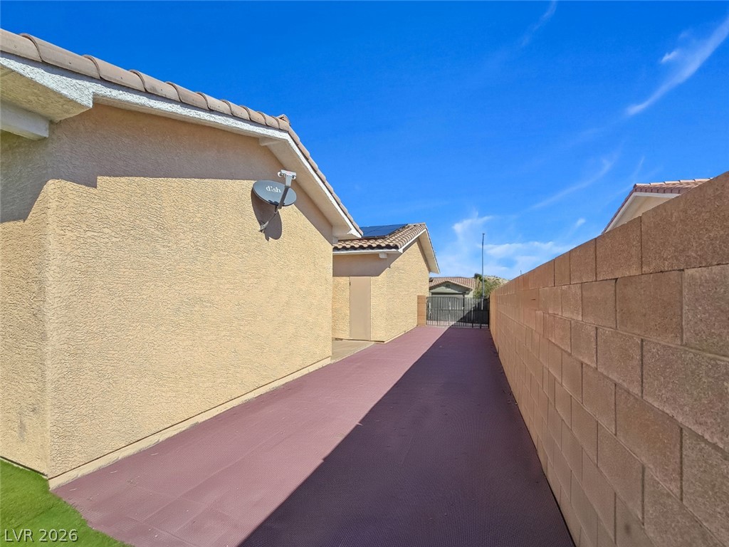 2485 Morrow Ridge Place Laughlin, NV 89029 - Photo 27 of 34 An expansive side paved area runs alongside the stucco exterior wall under a clear blue sky.