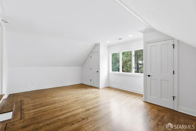 a view of a livingroom with wooden floor kitchen view and a window