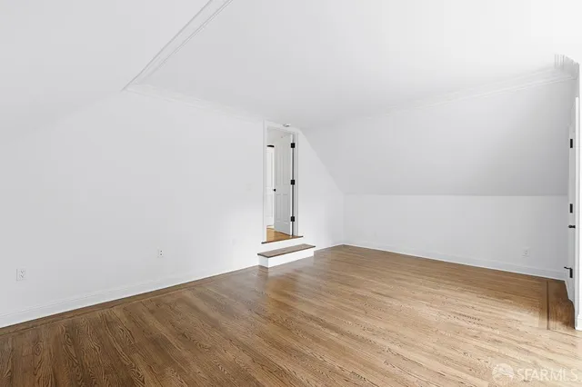 a view of empty room with wooden floor and windows