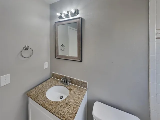 a bathroom with a granite countertop toilet sink and mirror
