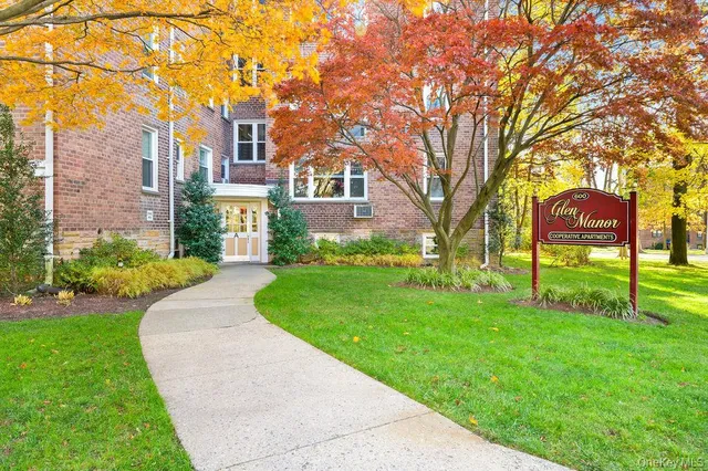 a view of a brick house with a big yard and large trees