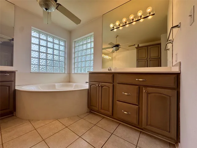 a spacious bathroom with a tub sink and mirror