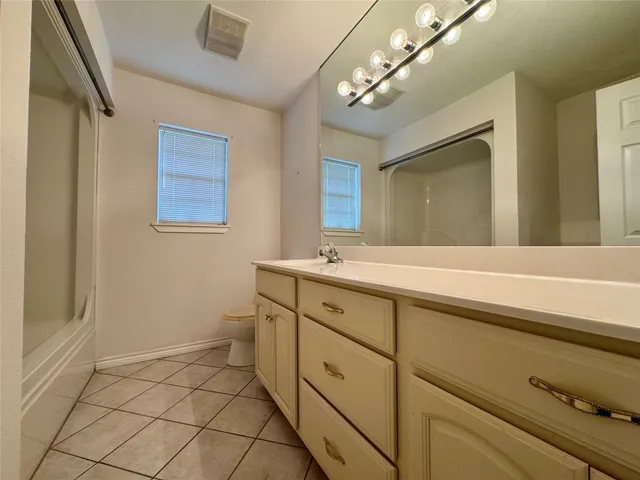 a spacious bathroom with a double vanity sink a toilet and a mirror