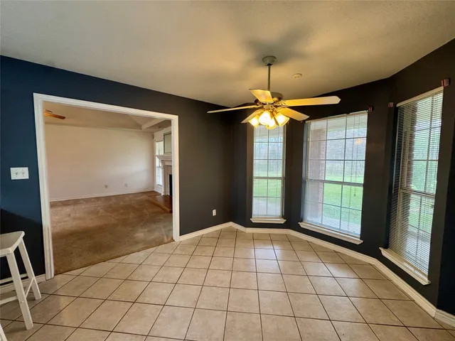 a view of an empty room with window and chandelier fan