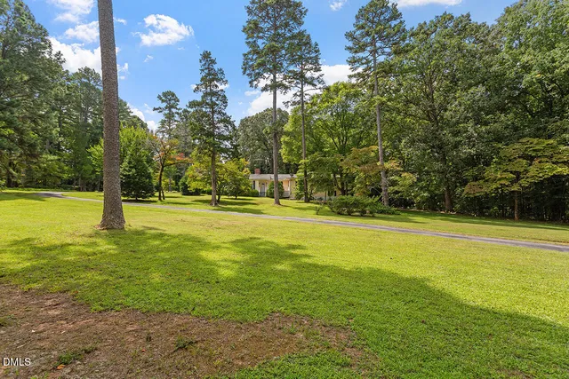 a view of a white house next to a yard with potted plants