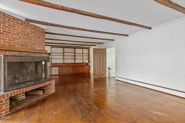 a view of an empty room with wooden floor a fireplace and a window