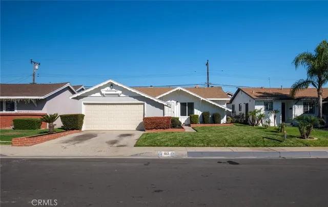a front view of a house with a yard and potted plants