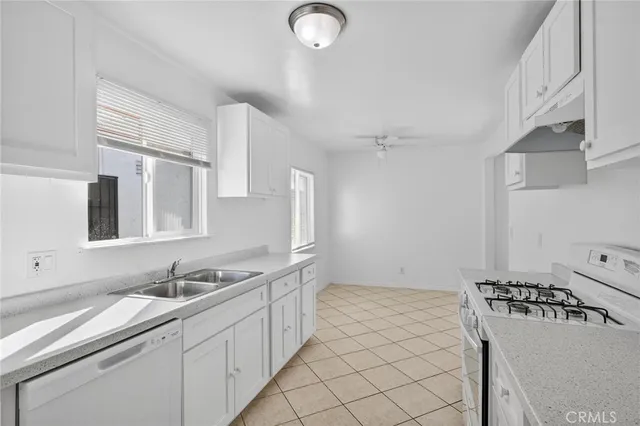 a kitchen with granite countertop a sink dishwasher stove and white cabinets