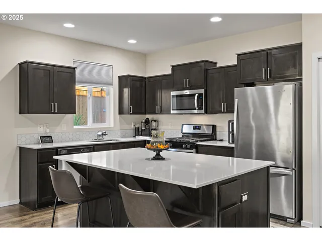 a kitchen with refrigerator sink dining table and chairs