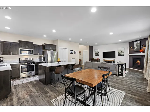a outdoor kitchen with a dining table chairs and flat screen tv