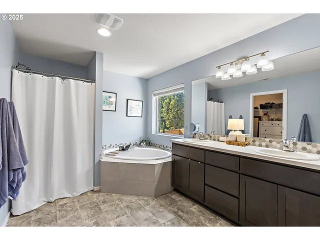 a bathroom with a double vanity sink mirror and bathtub