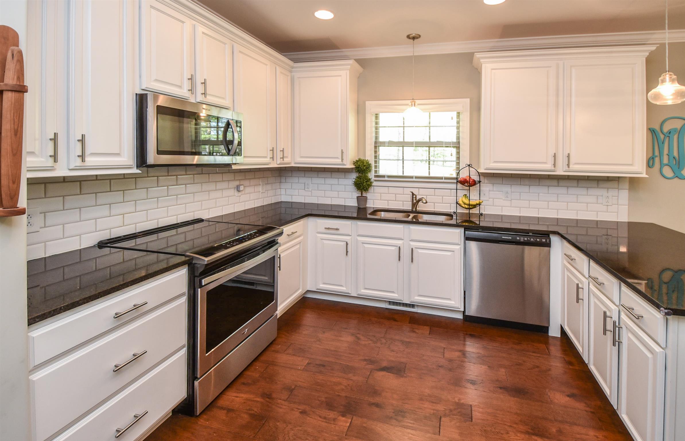 310 Independence Street Springfield, TN 37172 - Photo 19 of 29 a white kitchen with granite countertop a sink a stove a window and cabinets