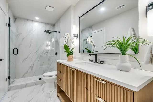a bathroom with a granite countertop sink a toilet and shower