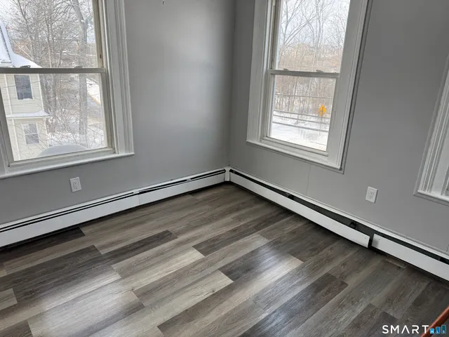 an empty room with wooden floor and windows