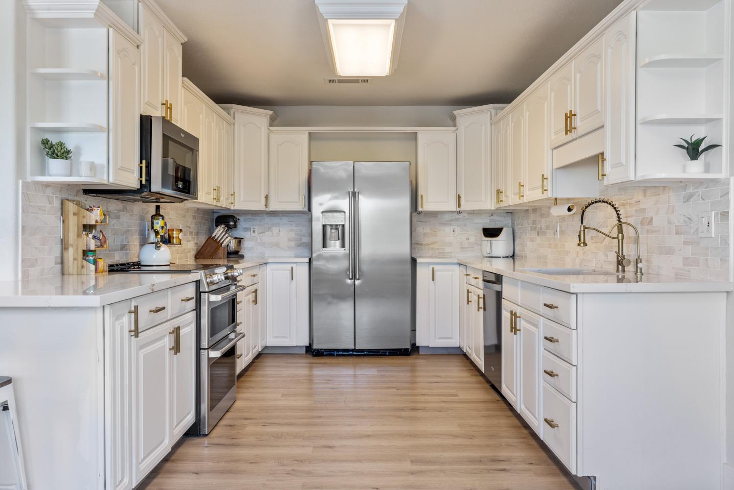 8300 Jantzen Road Modesto, CA 95357 - Photo 16 of 73 a kitchen with stainless steel appliances granite countertop a refrigerator a stove top oven a sink and dishwasher with wooden floor