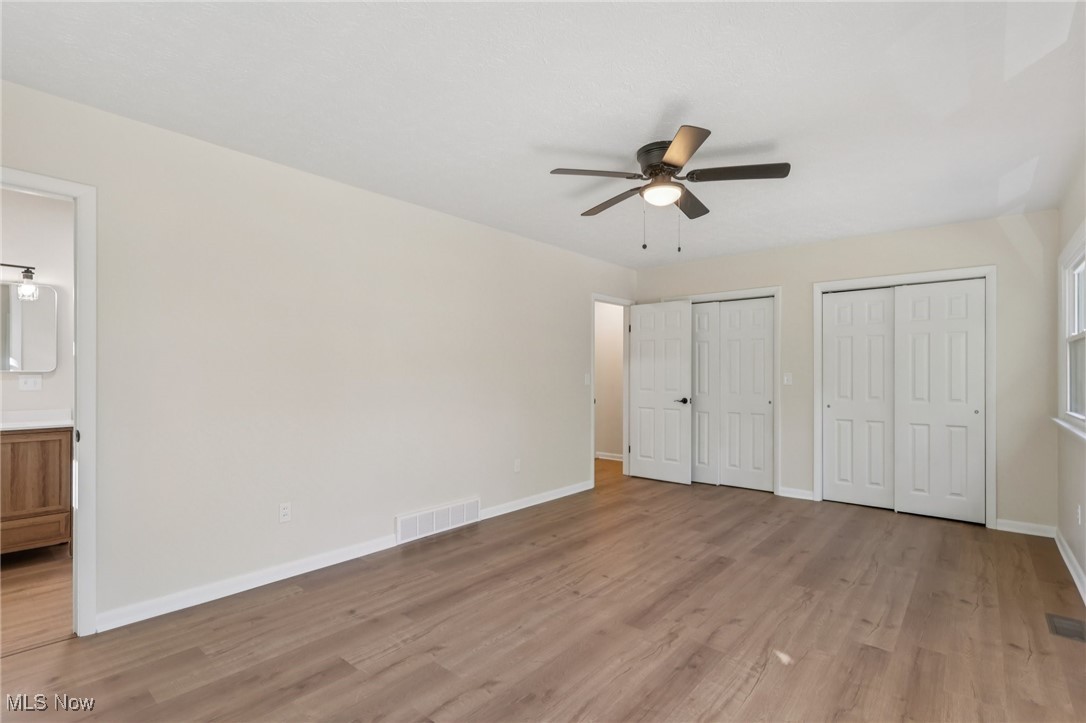50963 Becker Road Oberlin, OH 44074 - Photo 25 of 37 Unfurnished bedroom with multiple closets, light wood-style flooring, a ceiling fan, and ensuite bath