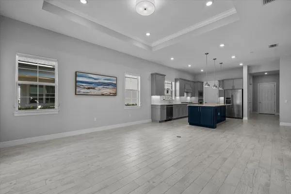 a large white kitchen with kitchen island a sink wooden floor and a large window