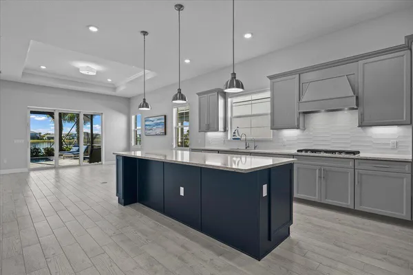 a kitchen with stainless steel appliances granite countertop wooden cabinets a sink a stove a kitchen island and a wooden floors