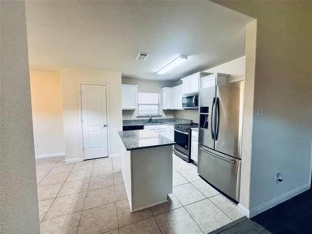 a kitchen with stainless steel appliances granite countertop a refrigerator and a stove top oven