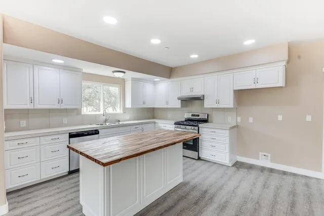 a kitchen with granite countertop a sink stove and cabinets