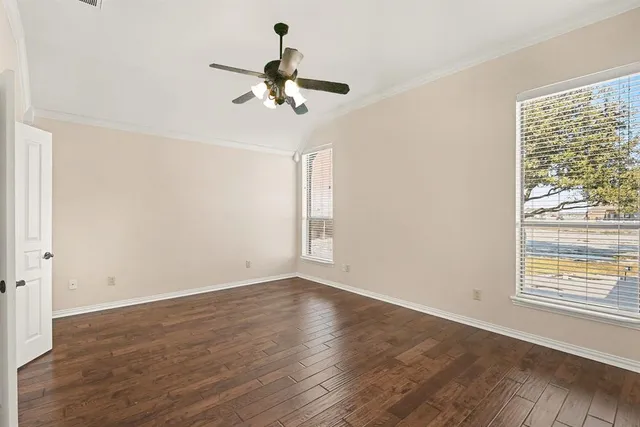 an empty room with wooden floor and a ceiling fan