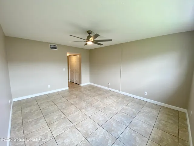 a view of an empty room and chandelier fan