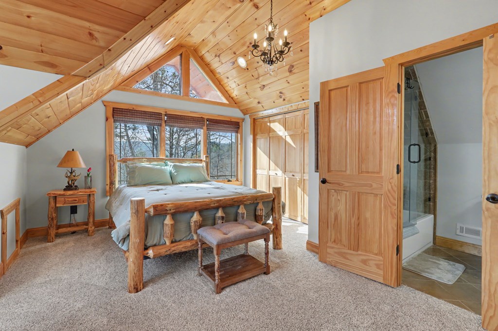 4760 Anderson Road Hiawassee, GA 30546 - Photo 59 of 104 a bedroom with a bed and a chandelier