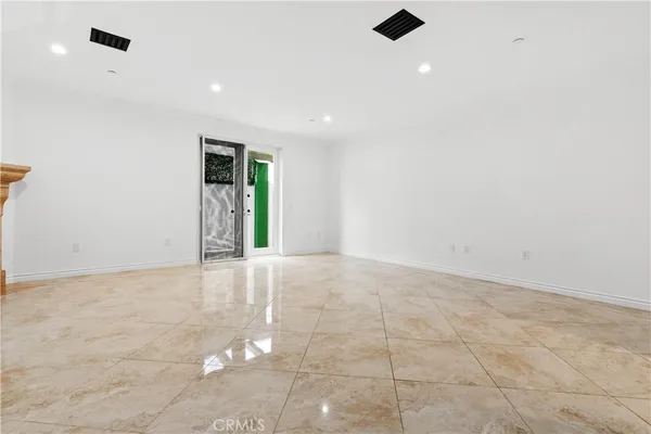 an empty room with an entryway and kitchen view