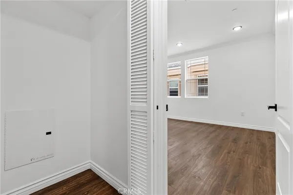 an empty room with wooden floor closet and windows