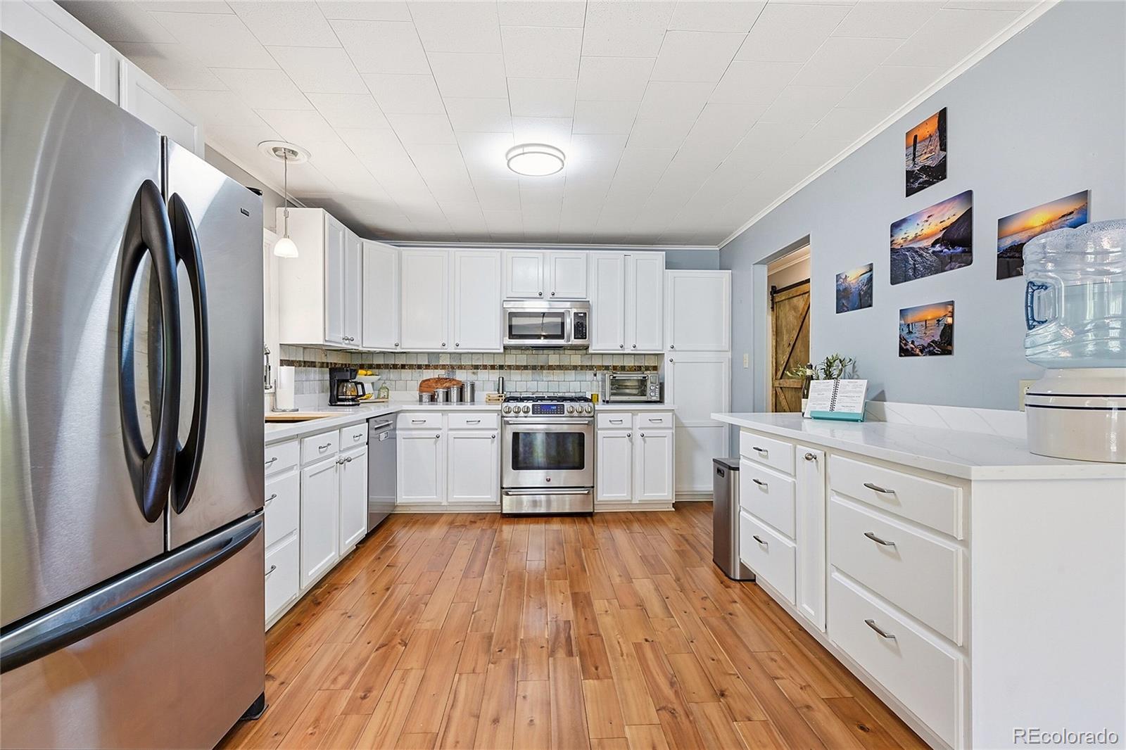 427 Brookside Drive Bailey, CO 80421 - Photo 4 of 37 a kitchen with white cabinets stainless steel appliances and wooden floor