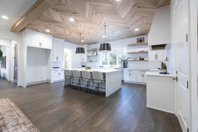a spacious bedroom with a bed mirror on table and a large window