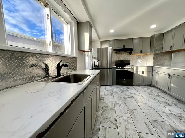 a kitchen with granite countertop a sink a counter top space stainless steel appliances and cabinets