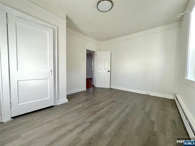 a view of an empty room with wooden floor and closet