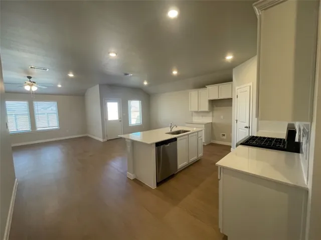 a kitchen with a sink a stove top oven a refrigerator and white cabinets
