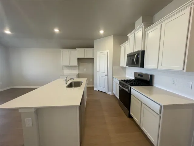 a large white kitchen with sink and refrigerator