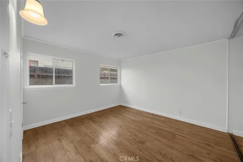 a view of an empty room with window and wooden floor