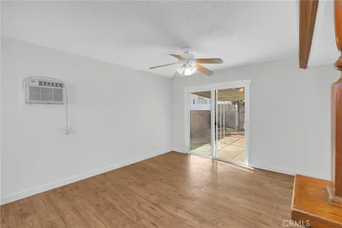 an empty room with wooden floor and ceiling fan