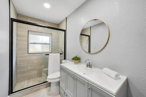a bathroom with a toilet a sink a mirror and a shower