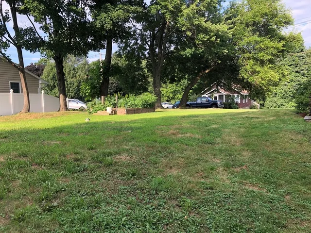 a view of a big yard with a house and large trees