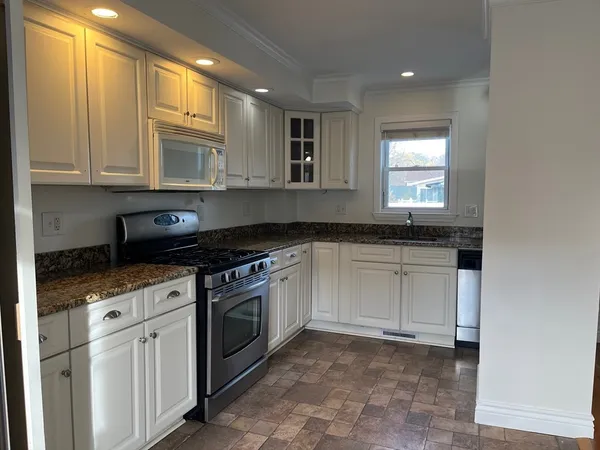 a kitchen with granite countertop white cabinets and stainless steel appliances