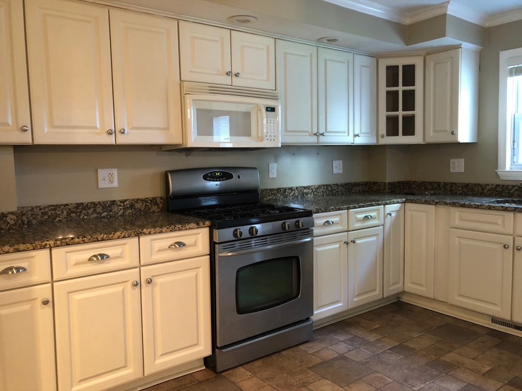 27 Pleasant Street, Unit 1 Middleton, MA 01949 - Photo 6 of 21 a kitchen with granite countertop white cabinets and stainless steel appliances