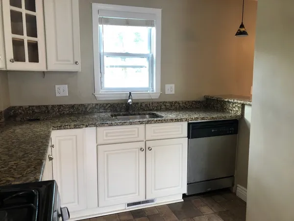 a kitchen with granite countertop white cabinets and a sink
