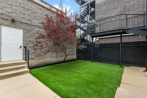 a view of a yard with brick wall and a large tree