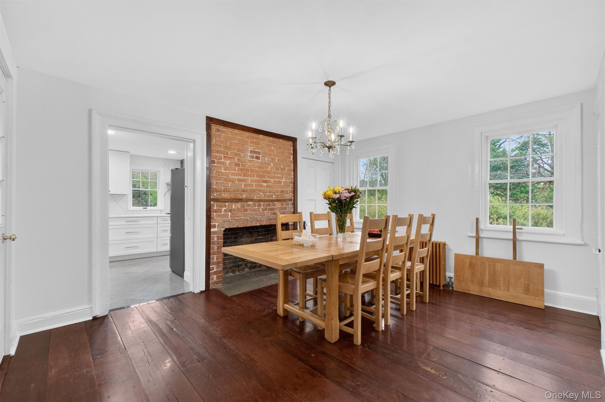 121 Old Glenham Road Fishkill, NY 12524 - Photo 15 of 50 Dining room featuring a prominent exposed brick fireplace, hardwood flooring, large windows and a doorway leading to the kitchen.